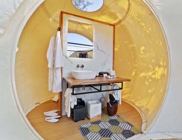 Your dome’s private bathroom features a contemporary sink, well-lit mirror, and thoughtful design—blending modern style with nature-inspired living.