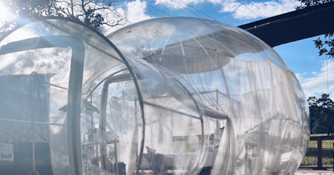 Clear bubble tent under blue sky.